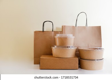 Bunch Of Blank Disposable Containers For Takeout Food Stacked With Paper Bags And Boxes With Copy Space For Brand's Logo. Close Up Shot Of Eco Friendly To Go Carton Bowls On Table.