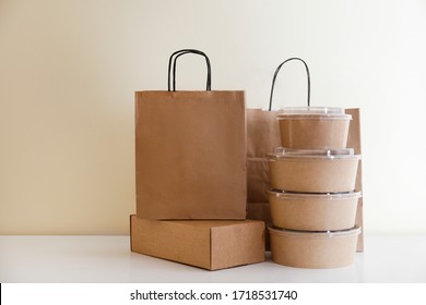 Bunch Of Blank Disposable Containers For Takeout Food Stacked With Paper Bags And Boxes With Copy Space For Brand's Logo. Close Up Shot Of Eco Friendly To Go Carton Bowls On Table.