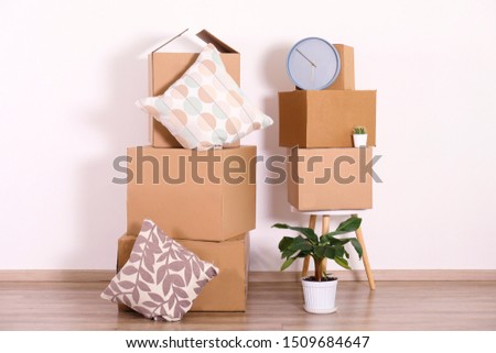 Bunch of blank unsigned moving boxes in new empty apartment. Spacious unfurnished room with unpacked cardboard box stack. Interior background, copy space for text.