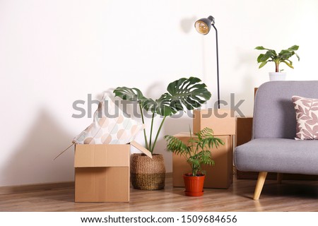Bunch of blank unsigned moving boxes in new empty apartment. Spacious unfurnished room with unpacked cardboard box stack. Interior background, copy space for text.