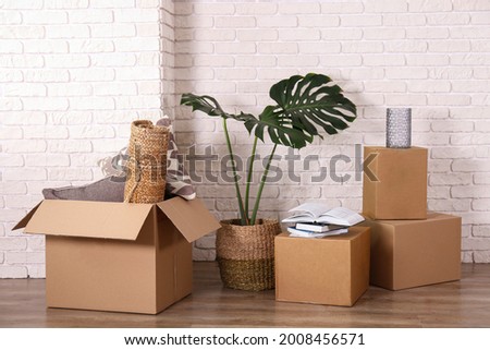 Bunch of blank unsigned moving boxes in new empty apartment. Spacious unfurnished room with unpacked cardboard box stack. Interior background, copy space for text.