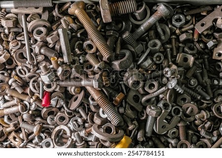 a bunch of bolts, nuts, washers made of metal lies in a box, vertically