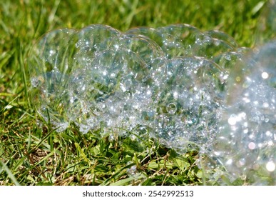A bunch of bubbles are floating on the grass. The bubbles are all different sizes and shapes, and they are scattered throughout the field. The scene is peaceful and serene