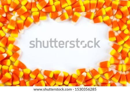 Bunch of candy corn sweets as symbol of Halloween holiday on textured background with a lot of copy space for text. Flat lay composition for all hallows eve. Top view shot.