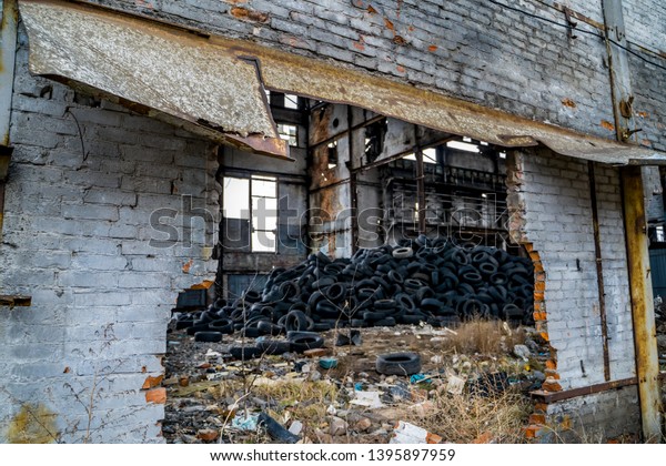 A bunch of car tires are in an\
abandoned factory. View of old factory inside.\
Close-up.