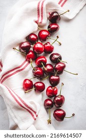 A Bunch Of Cherries With A White Kitchen Rag, On A White Board