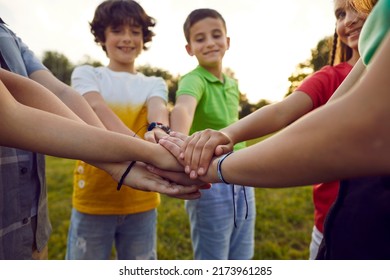 Bunch of children playing together on a good summer day. Group of happy friends standing in a circle in a green park or field, smiling and stacking their hands. Cropped closeup shot. Teamwork concept - Powered by Shutterstock