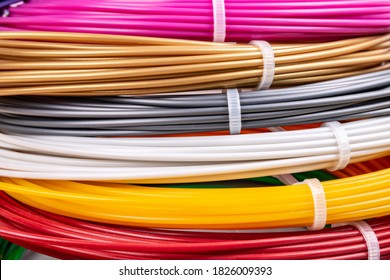 Bunch of colorful rolled cables. Closeup of plastic bright wires for 3D printer lying indoors, white studio background. Concept of children's entertainment and creativity.