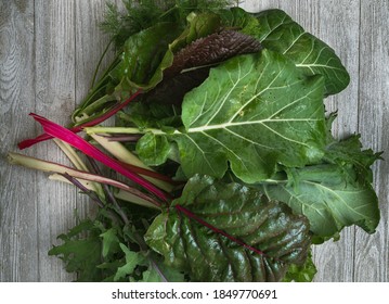 Bunch Of Dark Leafy Greens On A Wooden Table.