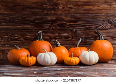 Bunch of decorative mini pumpkins of different kind, size and color on grunged wooden table background as a symbol of autumnal holidays with a lot of copy space for text.