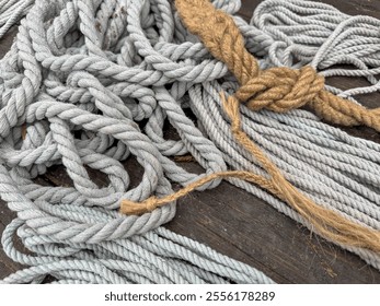 A bunch of different colored strings are tangled together on a wooden surface. The strings are of various sizes and colors, creating a visually interesting and chaotic scene
