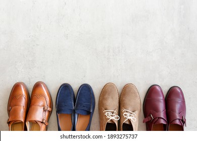 Bunch of different style men's shoes in a row isolated on white background. Chukka boots, penny loafers and double monk strap oxford shoes. Top view, copy space for text, close up, flat lay.