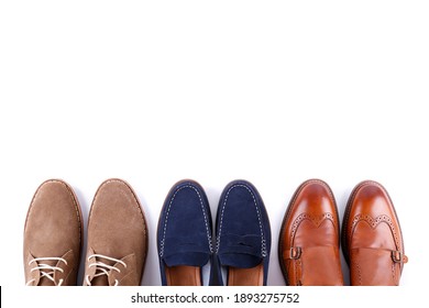 Bunch Of Different Style Men's Shoes In A Row Isolated On White Background. Chukka Boots, Penny Loafers And Double Monk Strap Oxford Shoes. Top View, Copy Space For Text, Close Up, Flat Lay.