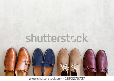 Bunch of different style men's shoes in a row isolated on white background. Chukka boots, penny loafers and double monk strap oxford shoes. Top view, copy space for text, close up, flat lay.