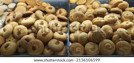 Bunch of digestive wheat glucose biscuit with cashew nut and badam scatered in plate inside bakery shop. Indian round shape biscuit known as chai snack or tea biscuits Close up macro flat lay top view