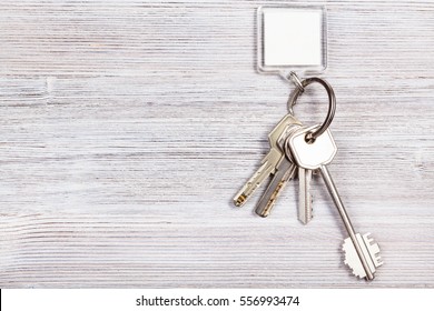 Bunch Of Door Keys With White Blank Key Chain On Wooden Board