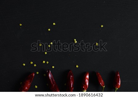 bunch of dry red hot chili peppers aligned on the bottom, with seeds, with space for your text on black background.