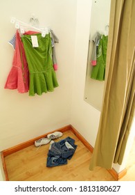 A Bunch Of Female Apparel In A Trial Room With A Mirror And Curtain.