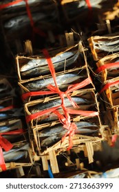 A bunch of fish are in a crate with red string tied around them. The fish are stacked on top of each other in a wooden crate