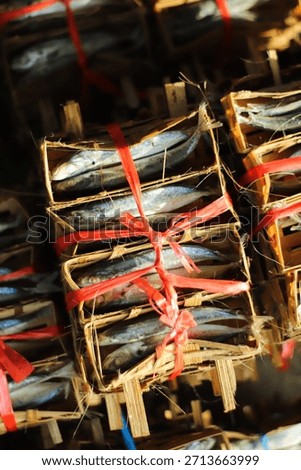 A bunch of fish are in a crate with red string tied around them. The fish are stacked on top of each other in a wooden crate