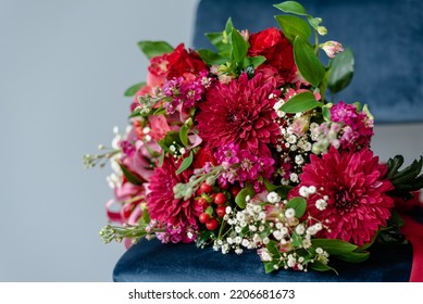 Bunch Of Flowers In Burgundy Tones On A Dark Blue Velvet Chair.