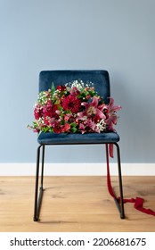 Bunch Of Flowers In Burgundy Tones On A Dark Blue Velvet Chair.