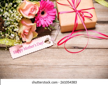 Bunch of flowers and tag with text on wooden background. Happy Mothers Day