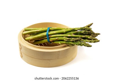 A Bunch Of Fresh Asparagus Spears In A Bamboo Vegetable Steamer Isolated On White