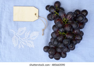 Bunch Of Fresh Organic Purple,black Grapes On A Empty Copy Space Vintage Tea Towel Background With A Blank Label Tag.