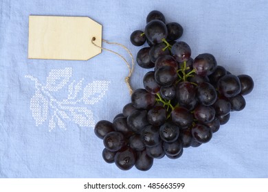 Bunch Of Fresh Organic Purple,black Grapes On A Empty Copy Space Vintage Tea Towel Background With A Blank Label Tag.