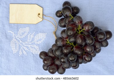 Bunch Of Fresh Organic Purple,black Grapes On A Empty Copy Space Vintage Tea Towel Background With A Blank Label Tag.