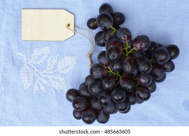 Bunch Of Fresh Organic Purple,black Grapes On A Empty Copy Space Vintage Tea Towel Background With A Blank Label Tag.