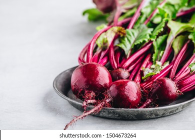 Bunch of fresh raw organic beets with leaves on a gray stone background