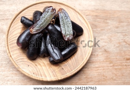 Bunch of fresh Sweet black seedless Moon Drops grape,Purple Witch Finger grapes,Sapphire Grapes or Witch Fingers grape in a white wooden dishisolated on wooden table backdrop.black grapes.  Stock photo © 