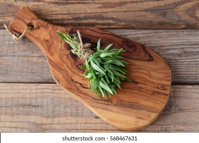A bunch of fresh tarragon on a wooden cutting board