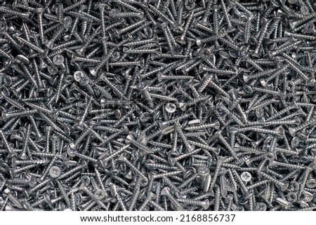 Bunch of galvanized stainless screws with flat countersink head, hardware background. Stack galvanized silver screws in toolbox for woodworking, metalworking and construction work with fasteners