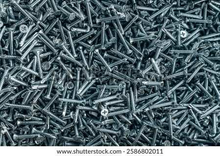 Bunch of galvanized stainless screws with flat countersunk head, hardware background.