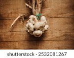 A bunch of garlic bulbs hanging on a rustic wooden background. Perfect for adding a touch of rustic charm to your culinary or food-related projects.