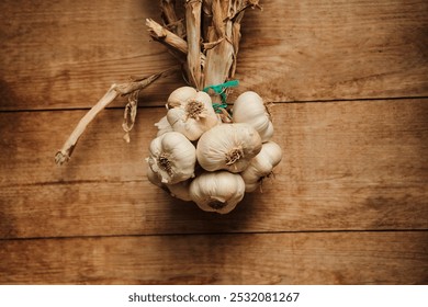 A bunch of garlic bulbs hanging on a rustic wooden background. Perfect for adding a touch of rustic charm to your culinary or food-related projects. - Powered by Shutterstock