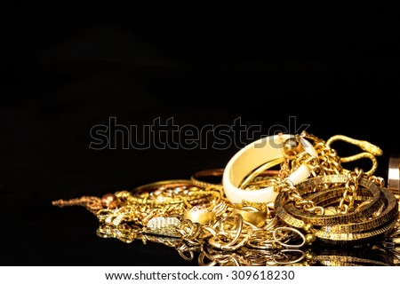 Bunch of gold jewelry against black background with copy space for text.
