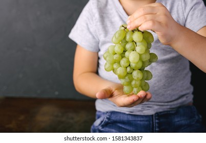 A Bunch Of Green Grapes In The Hands Of A Boy