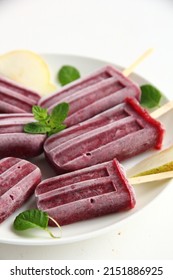 A Bunch Of Homemade Vegan Healthy Berry Purple Popsicles On A White Background With Pieces Of Pear And Mint Leaves