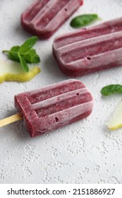 A Bunch Of Homemade Vegan Healthy Berry Purple Popsicles On A White Background With Pieces Of Pear And Mint Leaves