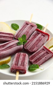 A Bunch Of Homemade Vegan Healthy Berry Purple Popsicles On A White Background With Pieces Of Pear And Mint Leaves