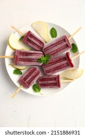 A Bunch Of Homemade Vegan Healthy Berry Purple Popsicles On A White Background With Pieces Of Pear And Mint Leaves