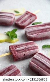 A Bunch Of Homemade Vegan Healthy Berry Purple Popsicles On A White Background With Pieces Of Pear And Mint Leaves