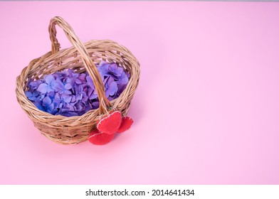 A Bunch Of Hydrangea Flowers On A Woven Basket Isolated On Pink Background With Copyspace