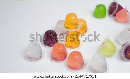 A bunch of jelly beans with different colored lids. The containers are filled with a jelly-like substance