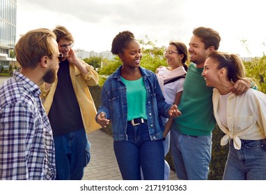 Bunch of joyful diverse college friends meet up in the city. Group of happy beautiful young multi ethnic Caucasian, Afro American and Asian people standing on the street, chit chatting and laughing - Shutterstock ID 2171910363