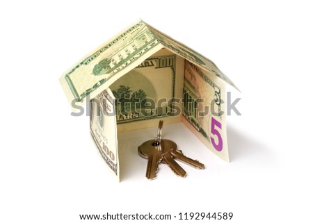 bunch of keys inside a house made from dollar banknotes on white background